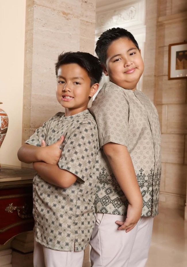 Kedua anak laki-laki Ardi dan Nia, Mainaka dan Magika, tampak mengenakan kemeja koko bermotif warna coklat muda. Kemeja tersebut dipadukan dengan celana panjang berwarna krem. Foto: Instagram/@ramadhaniabakrie/@geulis.id
