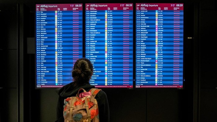 A passenger looks at the monitor displaying canceled flights at the Berlin-Brandenburg airport, Germany, Monday, March 10, 2025. (AP Photo/Ebrahim Noroozi)