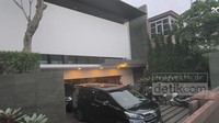 Terlihat rumahnya memiliki garasi serta carport yang muat untuk dua mobil. Lantai carport bermotif garis hitam dan putih.