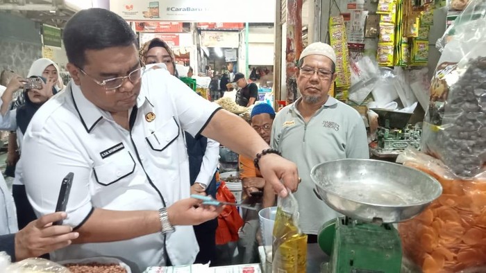 Kabid PDN Disperindag ESDM Sumut Charles Situmorang saat menakar ukuran Minyakita di salah satu pasar tradisional di Medan. (Dok. Disperindag ESDM Sumut)