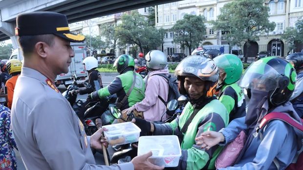 Kapolres Metro Jakarta Barat Kombes Twedi Aditya Benyahdi membagikan takjil kepada pengendara ojol.