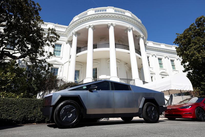 U.S. President Donald Trump talks to the media next to Tesla CEO Elon Musk, with Tesla cars in the background, at the White House in Washington, D.C., U.S., March 11, 2025. REUTERS/Kevin Lamarque