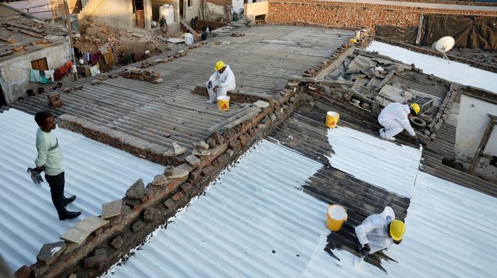 Painters apply liquid-applied membrane (LAM) coating that according to the authorities helps to bring down the temperature inside the shanties at a slum in Ahmedabad, India, January 30, 2025. REUTERS/Amit Dave