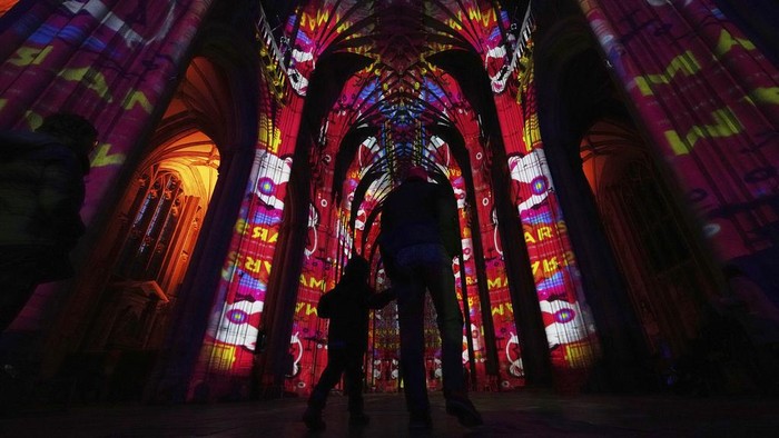 Warna-warni Seni Cahaya Sinari Makam Jane Austen di Katedral Winchester A sound and light show with a literary theme developed by Luxmuralis is screened inside Winchester Cathedral in Winchester, England, Tuesday, March 11, 2025. (AP Photo/Alastair Grant)