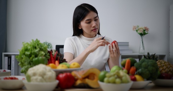 1497907514 Close up, Young female nutritionist checking fruits and vegetables on desk while analysis about information on document, correct nutrition and diet concept.
