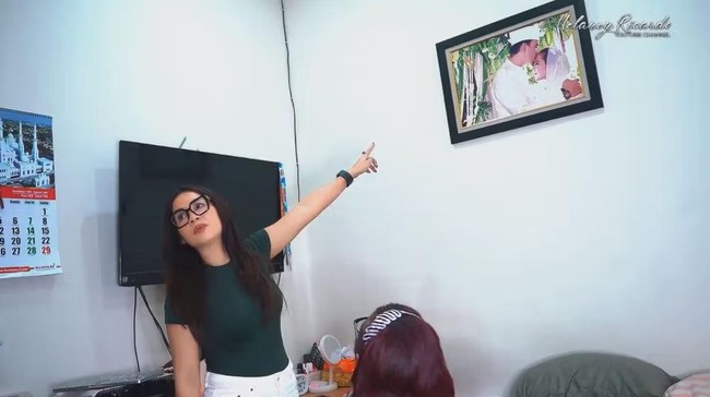 Di dalam kamar kos tersebut tampak terpajang foto nikah Nunung dan Iyan. Diakui Nunung bahwa dirinya mengalami masalah ekonomi sehingga kini terpaksa tinggal di kosan sederhana. Sejak tahun 2019 ia sudah mulai menjual beberapa aset miliknya. Foto: YouTube/Melaney Ricardo