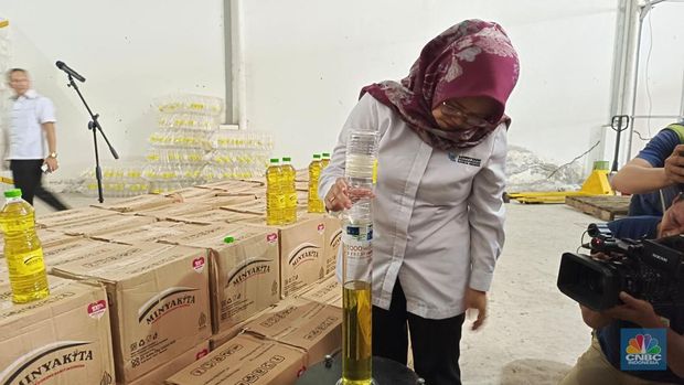 Seorang staff Kementerian Perdagangan memeriksa produk Minyakita dari PT AEGA terbukti kurang dari 1 liter, yakni hanya terisi 800,2 ml pada Kamis (13/3/2025). (CNBC Indonesia/Martyasari Rizky)