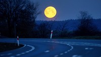 The moon sets behind a road in Wehrheim near Frankfurt, Germany, Thursday, March 13, 2025. (AP Photo/Michael Probst)