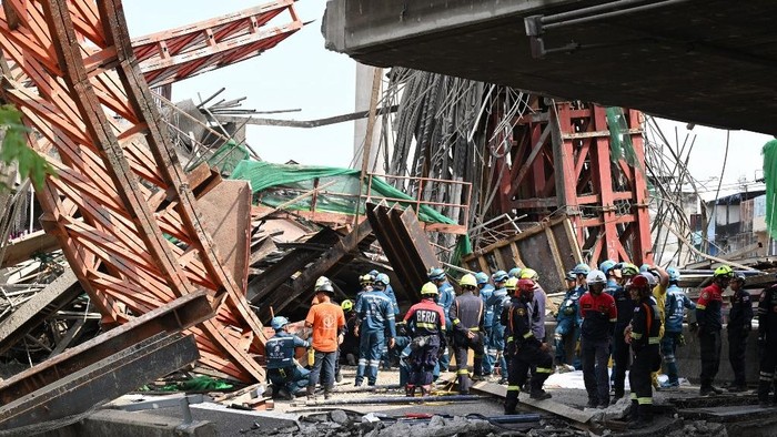 Emergency rescue workers survey the site of a crane collapse at a construction site along Rama II highway in Bangkok on March 15, 2025. A crane collapse at a construction site in Bangkok on March 15 killed at least 5 people, police said, as rescue teams worked to retrieve bodies from the debris. (Photo by Panumas SANGUANWONG / THAI NEWS PIX / AFP)