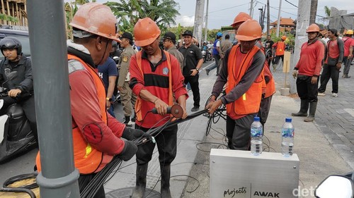 Tim PJUT Badung menurunkan kabel provider di sepanjang Jalan Nelayan, Canggu, Kuta Utara, Sabtu (15/3/2025). (Agus Eka/detikBali)