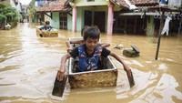 Sejumlah anak bermain perahu di lokasi banjir Dayeuhkolot, Kabupaten Bandung, Jawa Barat, Minggu (16/3/2025).