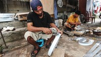 Sejumlah perajin menyelesaikan pembuatan reklame huruf timbul di pinggir Kali Ciliwung, Jatinegara, Jakarta, Minggu (16/3/2025).