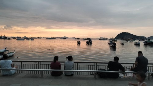Warga hingga turis ngabuburit dengan menikmati sunset dan kapal pinisi berlabuh di kawasan Marina Waterfront Labuan Bajo, Manggarai Barat, NTT, Minggu (16/3/2025). (Ambrosius Ardin/detiBali)