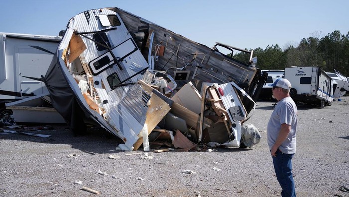 Lee Oliver, who works in sales, inspects the trailers and campers that lay torn apart at the Burton Campers saleyard after storms hit the area around Calera, Alabama, U.S, March 16, 2025.  REUTERS/Dane Rhys