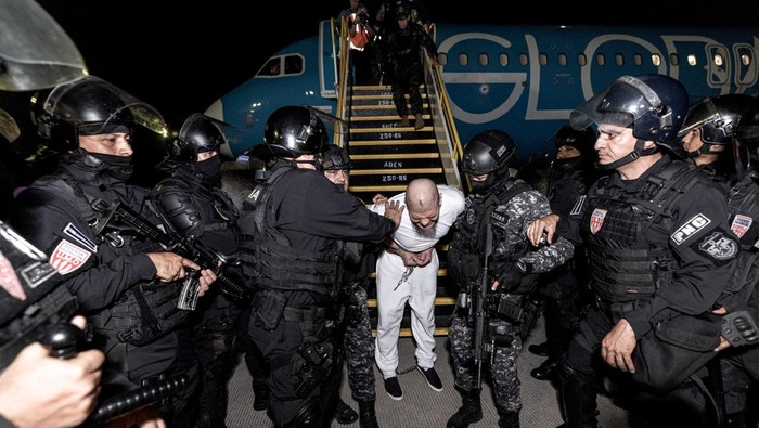 Meski Ditolak Pengadilan, Trump Kirim 238 Gangster ke Penjara El Salvador Salvadoran police officers escort alleged members of the Venezuelan gang Tren de Aragua recently deported by the U.S. government to be imprisoned in the Terrorism Confinement Center (CECOT) prison, as part of an agreement with the Salvadoran government, at the El Salvador International Airport in San Luis Talpa, El Salvador, in this handout image obtained March 16, 2025. Secretaria de Prensa de la Presidencia/Handout via REUTERS ATTENTION EDITORS - THIS IMAGE HAS BEEN SUPPLIED BY A THIRD PARTY. NO RESALES. NO ARCHIVES TPX IMAGES OF THE DAY