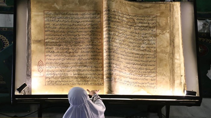 Pameran warisan intelektual ulama nusantara Pengunjung melihat Al Quran kuno yang ditulis tangan saat pameran warisan intelektual ulama nusantara di Masjid Nasional Al Akbar, Surabaya, Jawa Timur, Minggu (16/3/2025). Pameran yang diselenggarakan atas kerja sama Dinas Perpustakaan dan Kearsipan Jawa Timur bersama NU tersebut berlangsung hingga 24 Maret dengan menghadirkan berbagai koleksi naskah kuno dan infografis tentang perjuangan, pemikiran dan kontribusi ulama nusantara terhadap perkembangan Islam di Indonesia hingga internasional. ANTARA FOTO/Moch Asim/YU