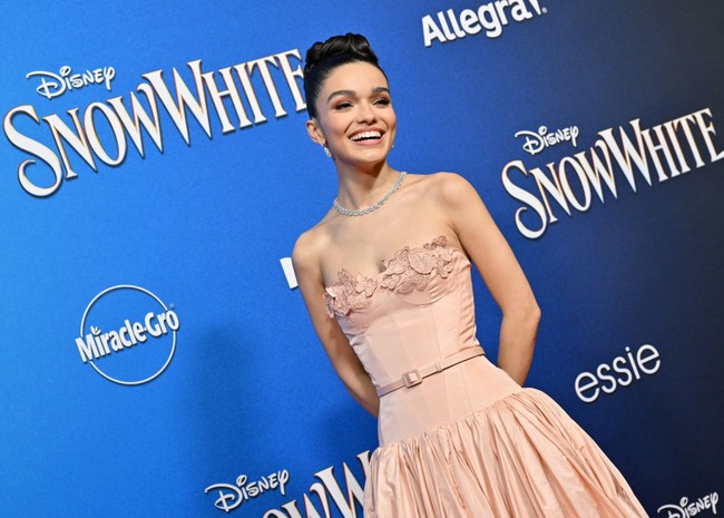 Rambutnya ditata dengan updo elegan, dipadukan aksesori berupa kalung berlian dan anting. Makeup-nya terlihat natural dengan riasan mata smoky, blush peach di pipi, serta lipstik bernuansa nude. Foto: Getty Images for Disney/Rodin Eckenroth