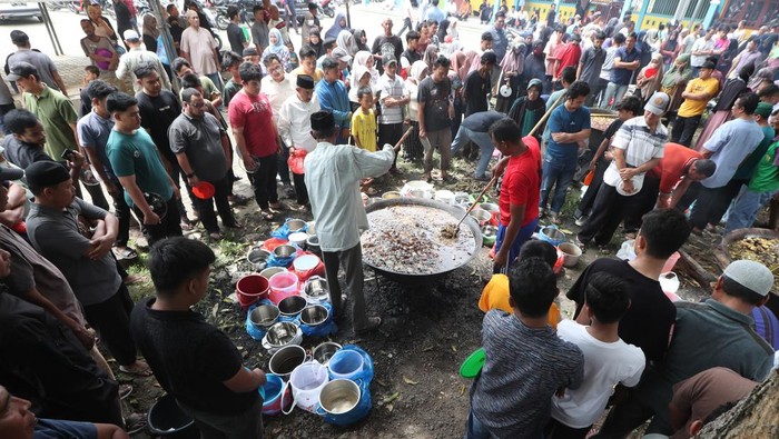 Warga antre mengambil menu kuliner tradisional kuah beulangong daging sapi pada perayaan kenduri Nuzulul Quran di Desa Doy Ulee Kareng, Banda Aceh, Aceh, Senin (17/3/2025). Menu kuliner tradisional khas Aceh kuah beulangong yang dimasak secara gotong royong untuk sajian berbuka puasa pada peringatan Nuzulul Quran 1446 Hijriah itu telah menjadi tradisi dan dibagikan kepada warga desa terutama keluarga fakir, miskin, dan anak yatim. ANTARA FOTO/Irwansyah Putra/rwa.