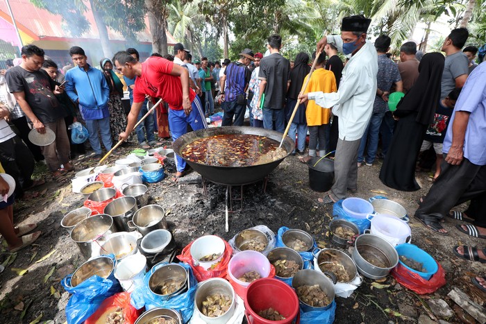 Warga antre mengambil menu kuliner tradisional kuah beulangong daging sapi pada perayaan kenduri Nuzulul Quran di Desa Doy Ulee Kareng, Banda Aceh, Aceh, Senin (17/3/2025). Menu kuliner tradisional khas Aceh kuah beulangong yang dimasak secara gotong royong untuk sajian berbuka puasa pada peringatan Nuzulul Quran 1446 Hijriah itu telah menjadi tradisi dan dibagikan kepada warga desa terutama keluarga fakir, miskin, dan anak yatim. ANTARA FOTO/Irwansyah Putra/rwa.