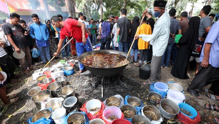Warga antre mengambil menu kuliner tradisional kuah beulangong daging sapi pada perayaan kenduri Nuzulul Quran di Desa Doy Ulee Kareng, Banda Aceh, Aceh, Senin (17/3/2025). Menu kuliner tradisional khas Aceh kuah beulangong yang dimasak secara gotong royong untuk sajian berbuka puasa pada peringatan Nuzulul Quran 1446 Hijriah itu telah menjadi tradisi dan dibagikan kepada warga desa terutama keluarga fakir, miskin, dan anak yatim. ANTARA FOTO/Irwansyah Putra/rwa.