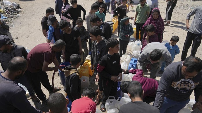 Warga Gaza Masih Krisis Air Bersih Palestinians fill cans with water in Jabaliya, northern Gaza Strip, Sunday, March 16, 2025. (AP Photo/Abdel Kareem Hana)