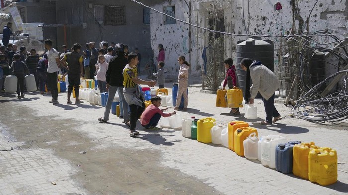 Palestinians fill cans with water in Jabaliya, northern Gaza Strip, Sunday, March 16, 2025. (AP Photo/Abdel Kareem Hana)