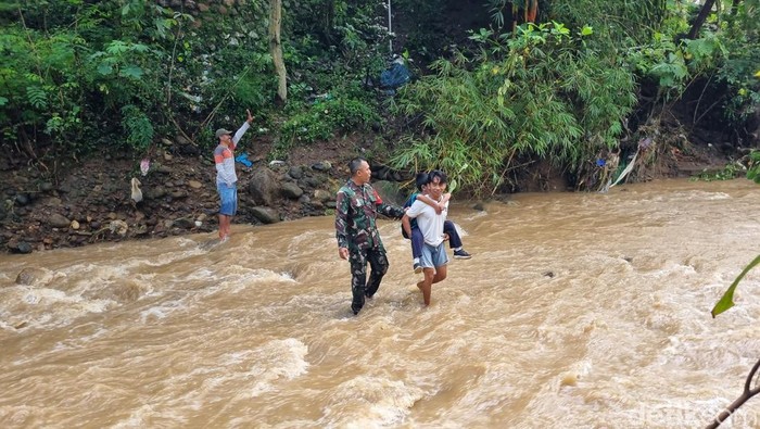 Pelajar saat menyeberang sungai berarus deras usai jembatan putus