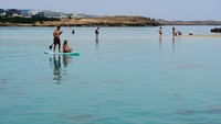 Sejumlah pengunjung menikmati cuaca hangat di laut dekat resort, Ayia Napa di Pulau Mediterania Timur, Siprus, Senin (17/3/2025).