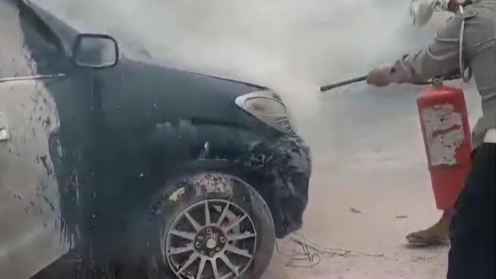 Petugas kepolisian saat mencoba membantu memadamkan api dari mobil yang terbakar di Cirebon