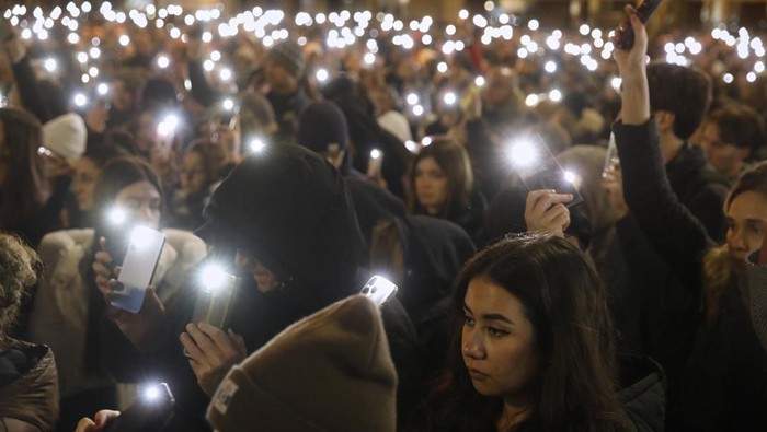A protester holds her mobile phone as thousands gather for the victims of a massive nightclub fire in the town of Kocani, in Skopje, North Macedonia, Tuesday, March 18, 2025. (AP Photo/Boris Grdanoski)
