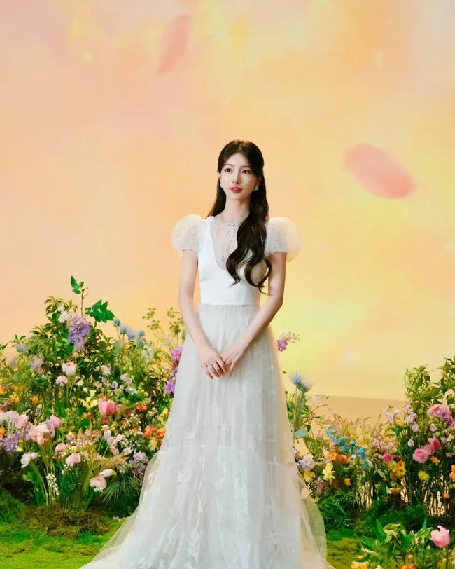 Idol 30 tahun ini kemudian terlihat berbalut gaun putih panjang setelah menanggalkan jubahnya. Gaun lace dengan lengan bervolume menampakkan sosok Suzy yang tampil bak Snow White. Foto: Instagram/@skuukzky