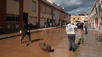 Warga membersihkan lumpur dari jalan usai banjir di Campanillas, Malaga, Spanyol, Selasa (18/3/2025).
