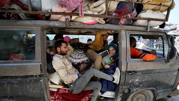 People sit as Palestinians make their way to flee their homes, after the Israeli army issued evacuation orders for a number of neighborhoods, following heavy Israeli strikes, in the northern Gaza Strip March 18, 2025. REUTERS/Mahmoud Issa