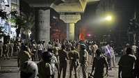Warga berdiri di samping kendaraan yang terbakar sehari setelah bentrokan komunal yang dipicu oleh protes yang menuntut pemindahan makam penguasa Muslim Mughal abad ke-17.