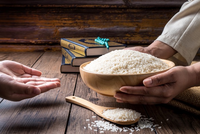 Hands are holding a pile of grain to zakat, the Islamic zakat concept. Muslims to help the poor and needy. Conceptual shoot for property, income, and fitrah zakat.