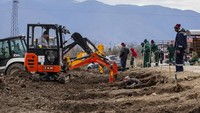 Para petugas menggunakan ekskavator untuk menggali deretan kuburan di Kocani saat kota tersebut menunggu pemakaman penduduk muda yang jenazahnya masih diproses untuk diidentifikasi.