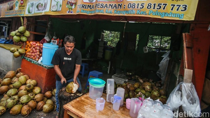 Pedagang membuka kelapa muda di Jalan Bangunan Barat, Rawamangun, Jakarta Timur, Kamis (20/3/2025).
