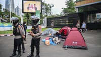 Polisi berjaga di depan pengunjuk rasa yang mendirikan tenda di depan pintu gerbang Pancasila, Gedung DPR RI, Jakarta, Kamis (20/3/2025).