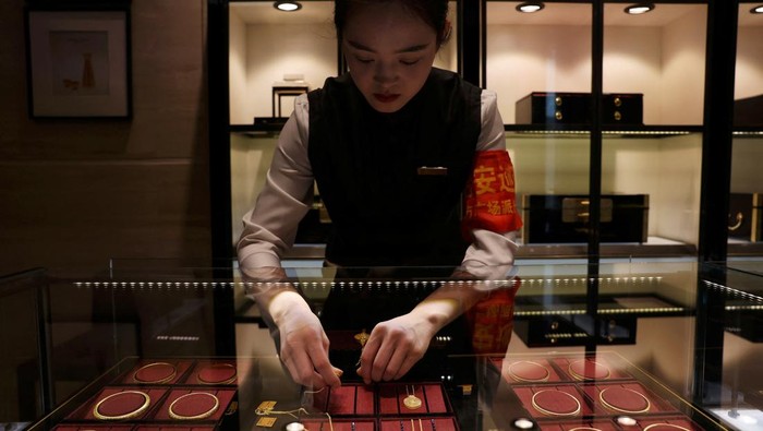 Staff members attend to customers at a Laopu Gold jewellery store in Beijing, China March 12, 2025. REUTERS/Florence Lo