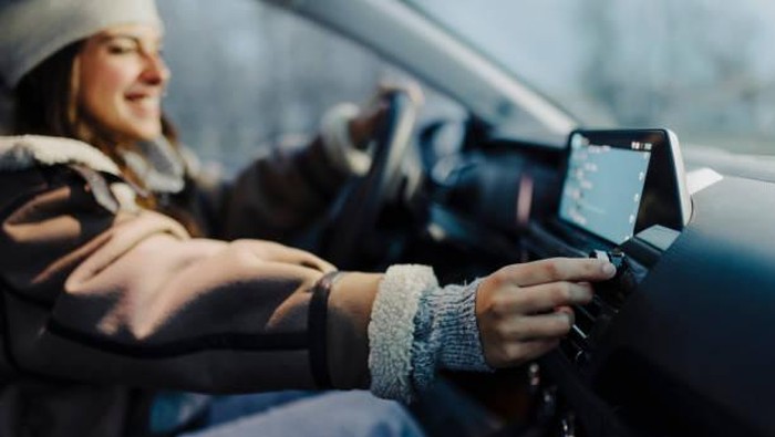 Smiling young woman using global positioning system while driving her car.