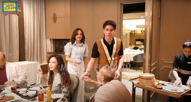 Datang terlambat, El dan Syifa Hadju langsung bersalaman lalu duduk dan ikut bersama-sama menyantap hidangan yang disediakan. Syifa tampil simpel kenakan crop top kemeja lengan balon dipadukan dengan celana panjang putih. Sementara El kenakan polo shirt hiitam dengan aksen coklat dipadukan celana panjang senada. Foto: YouTube/MAIA ALELDUL TV