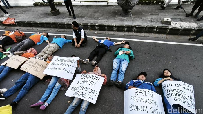 Massa buruh menggelar aksi tidur di jalan di depan rumah bos Sritex, Solo, Jumat (21/3/2025).