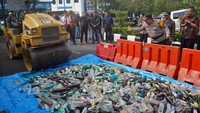 Personel polisi melempar botol minuman keras saat pemusnahan barang bukti minuman keras di Mapolres Temanggung, Jawa Tengah, Jumat (21/3/2025).