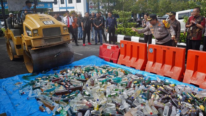 Personel polisi melempar botol minuman keras saat pemusnahan barang bukti minuman keras di Mapolres Temanggung, Jawa Tengah, Jumat (21/3/2025). Dalam kegiatan tersebut jajaran Polres Temanggung memusnahkan sebanyak 2.140 botol miras dan 2.653 knalpot tidak standar guna menciptakan keamanan dan kenyamanan masyarakat selama bulan Ramadhan dan Hari Raya Idul Fitri. ANTARA FOTO/Anis Efizudin/nz