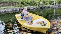 Ada lagi momen ketika ibunda Moana itu menikmati camilan burger hingga air kelapa muda di atas perahu. Pemandangannya pun langsung di atas kolam penuh ikan koi. Foto: Instagram @riaricis1795