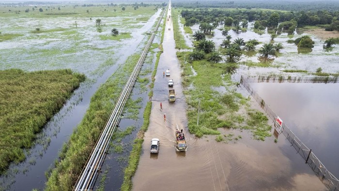Foto udara kendaraan melintasi jalan yang terendam banjir di Betara 10, Tanjung Jabung Barat, Jambi, Sabtu (22/3/2025). Banjir yang disebabkan luapan Sungai Pengabuan tersebut mengakibatkan akses jalan dari Tanjung Jabung Barat bagian hilir menuju sejumlah desa di bagian hulu terganggu, pengendara sepeda motor terpaksa menggunakan mobil bak terbuka dan truk untuk menyeberang dengan tarif Rp20 ribu. ANTARA FOTO/Wahdi Septiawan/Spt.