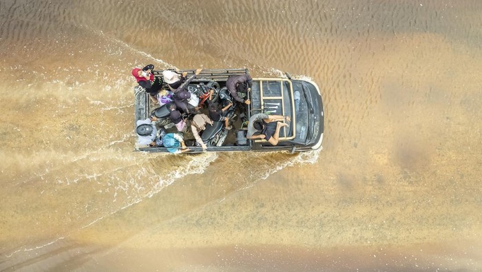 Banjir di Tanjung Jabung Barat Foto udara kendaraan melintasi jalan yang terendam banjir di Betara 10, Tanjung Jabung Barat, Jambi, Sabtu (22/3/2025). Banjir yang disebabkan luapan Sungai Pengabuan tersebut mengakibatkan akses jalan dari Tanjung Jabung Barat bagian hilir menuju sejumlah desa di bagian hulu terganggu, pengendara sepeda motor terpaksa menggunakan mobil bak terbuka dan truk untuk menyeberang dengan tarif Rp20 ribu. ANTARA FOTO/Wahdi Septiawan/Spt.