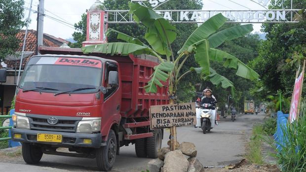 Pengendara motor melintas didekat pohon pisang yang ditanam pada jalan yang rusak di Kadilanggon, Wedi, Klaten, Jawa Tengah, Sabtu (22/3/2025). Warga setempat melakukan aksi menanam pohon pisang di sejumlah titik pada jalan penghubung antara Klaten, Jawa Tengah dengan Gunung Kidul, Daerah Istimewa Yogyakarta yang rusak akibat truk bermuatan tanah uruk. ANTARA FOTO/Aloysius Jarot Nugroho.