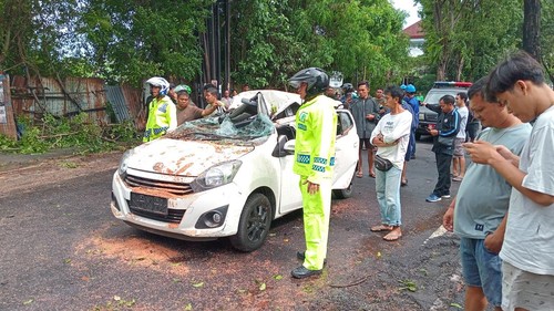Petugas mengevakuasi korban dan mobil tertimpa pohon tumbang di Jalan Raya Kuta, Badung, Sabtu (22/3/2025). (Aryo Mahendro/detikBali)