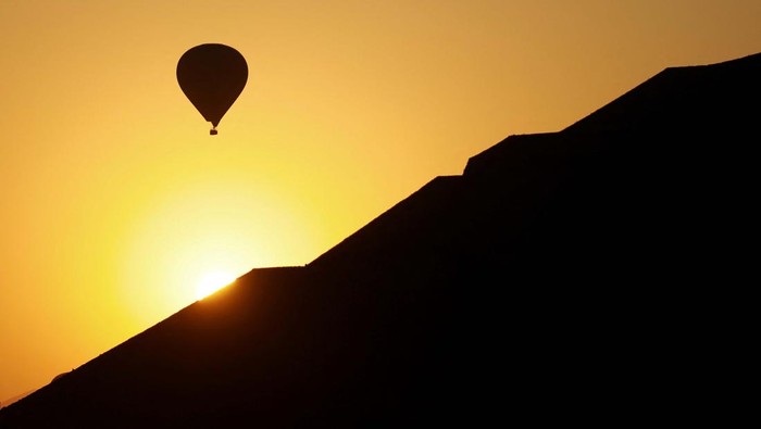 A hot air balloon floats near the Pyramid of the Sun, following the spring equinox, in the pre-hispanic city of Teotihuacan, on the outskirts of Mexico City, Mexico March 21, 2025 REUTERS/Raquel Cunha